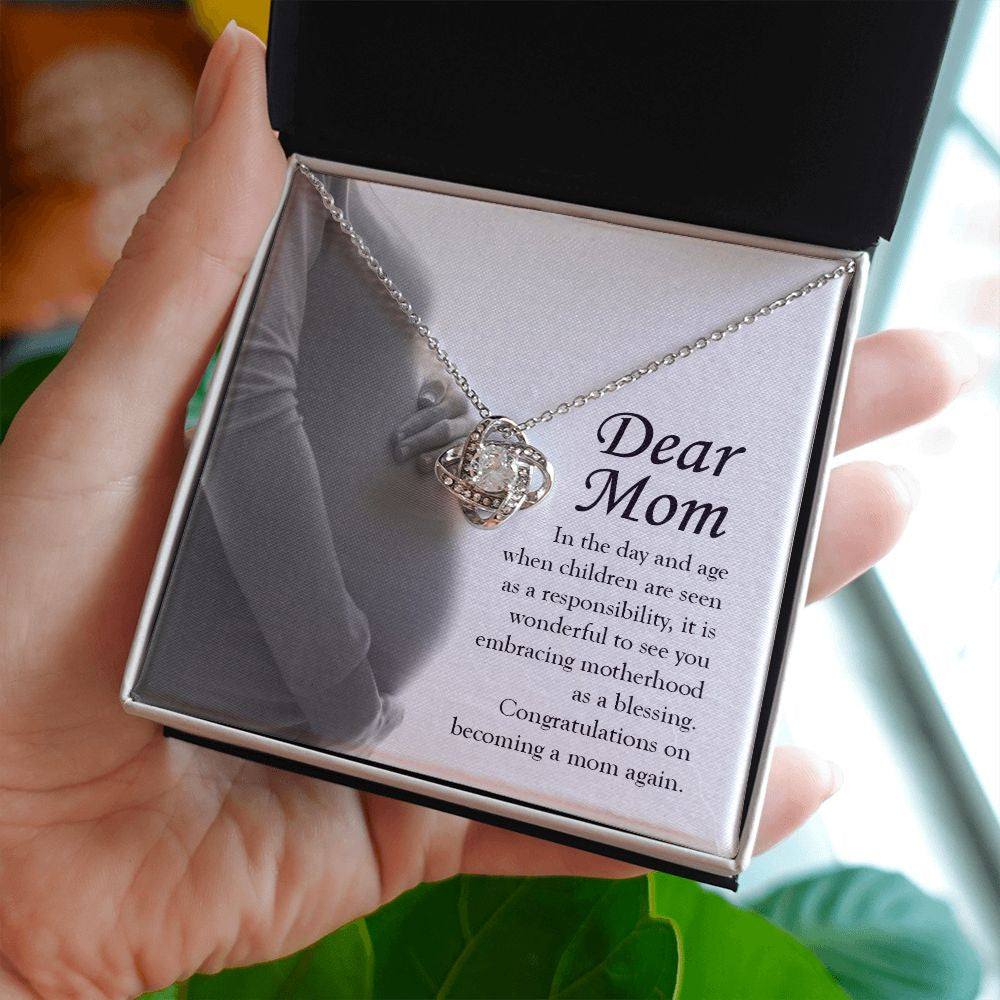 Embracing Motherhood Again love knot necklace in hand