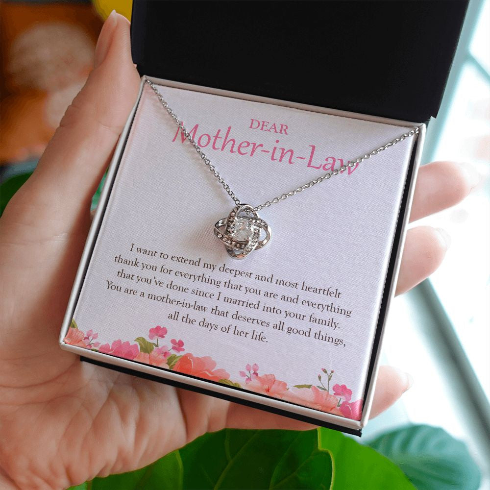 Deserves All The Good Things love knot necklace in hand