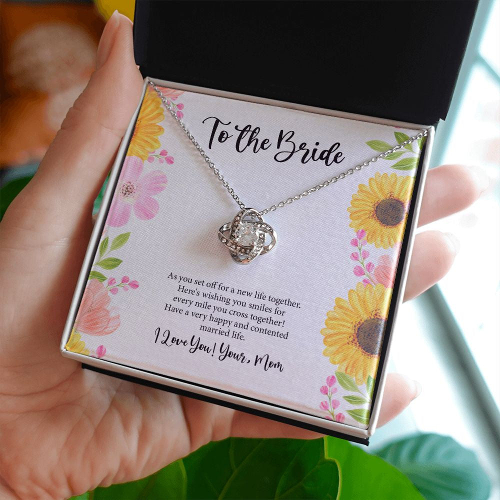 Every Mile You Cross love knot necklace in hand